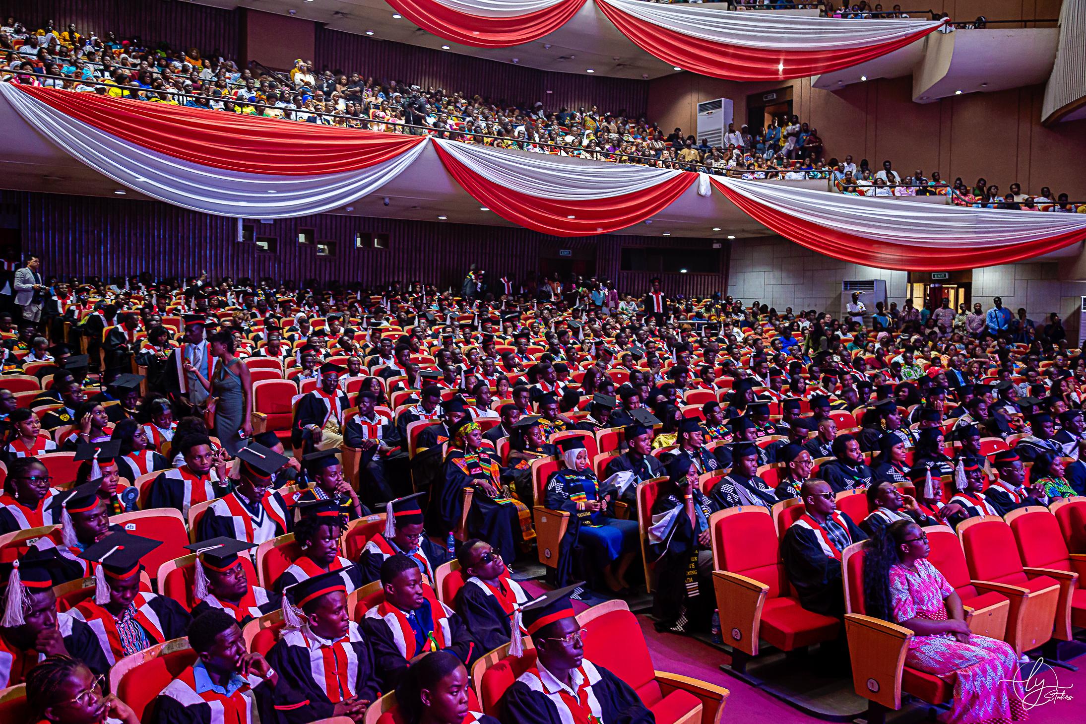 A packed modern auditorium of IPMC graduands in caps and gowns